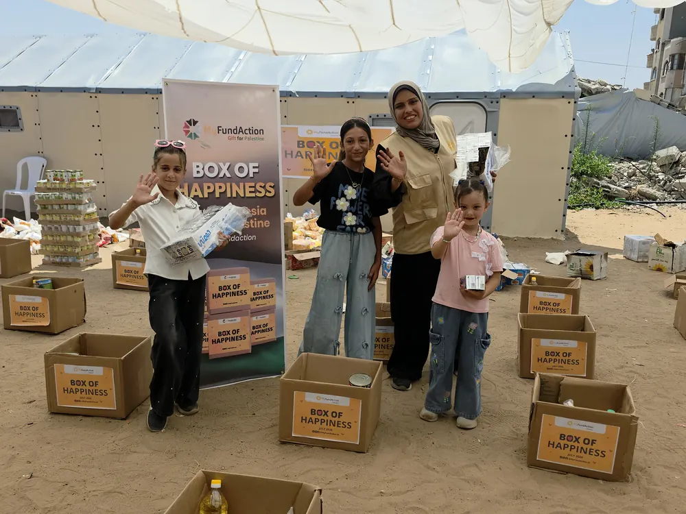 Children and a MyFundAction volunteer beside Box of Happiness food parcels being packed at a distribution point in Gaza