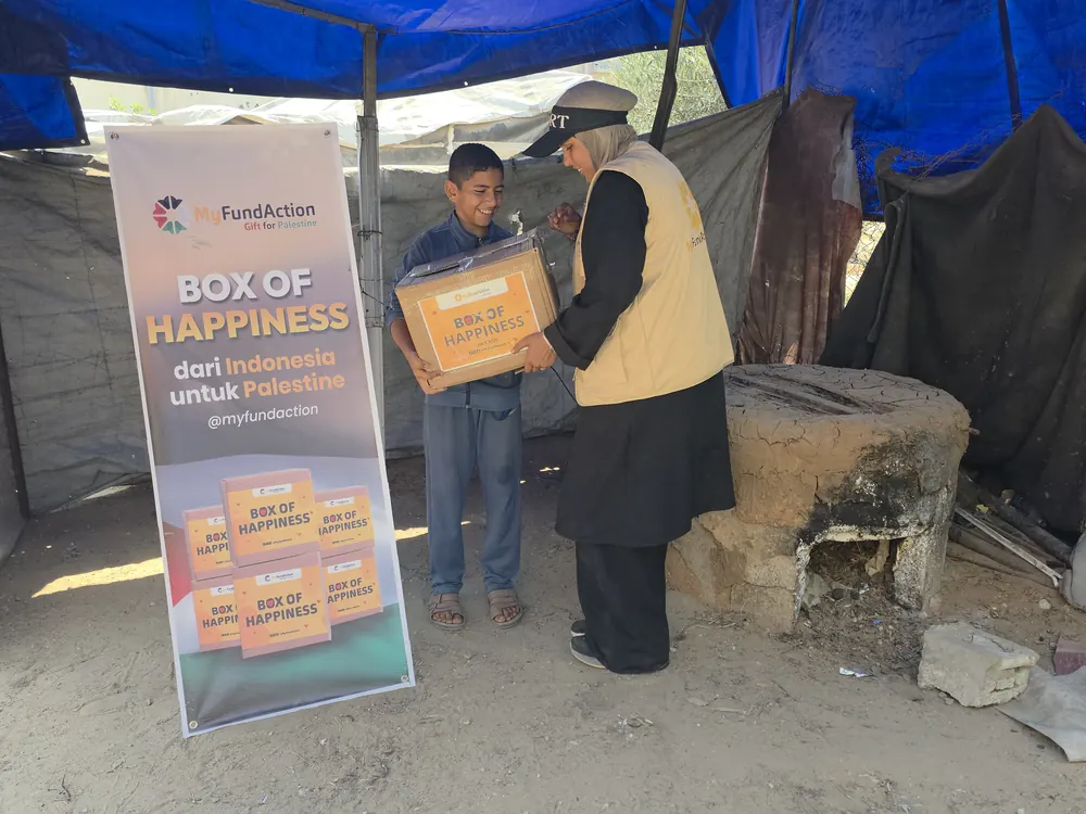 A MyFundAction volunteer handing a Box of Happiness food parcel to a boy at a shelter in Gaza