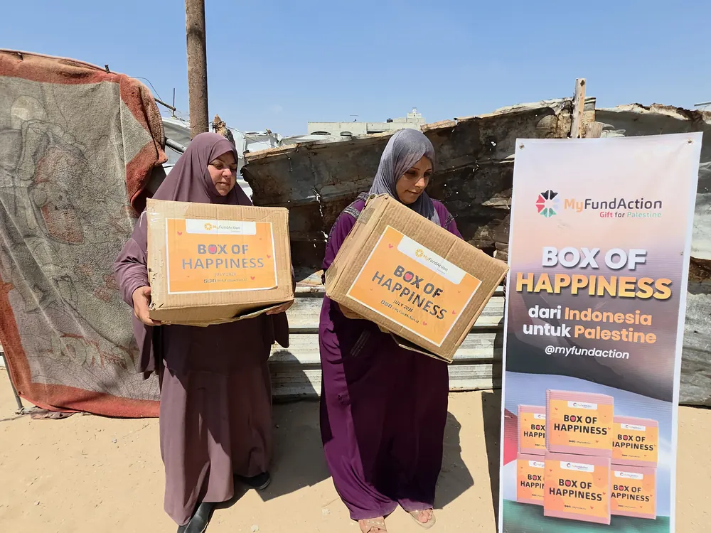 Two women carrying Box of Happiness food parcels home from a MyFundAction distribution in Gaza