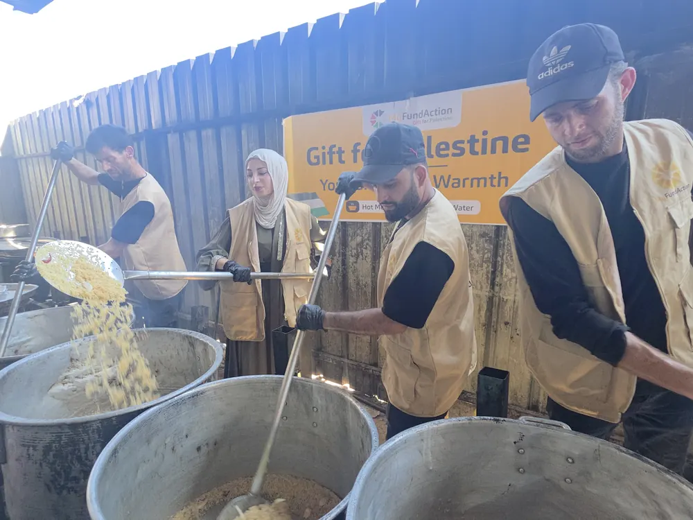 MyFundAction volunteers cooking hot meals in large pots at a community kitchen in Gaza
