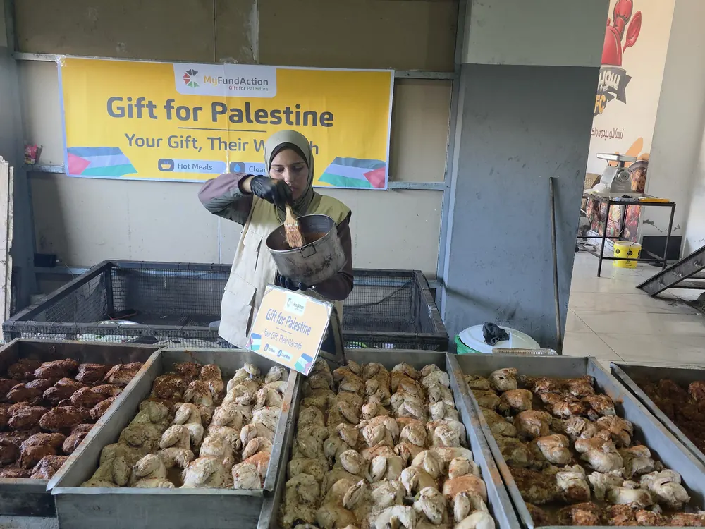 A MyFundAction volunteer preparing trays of roast chicken for hot-meal distribution in Gaza