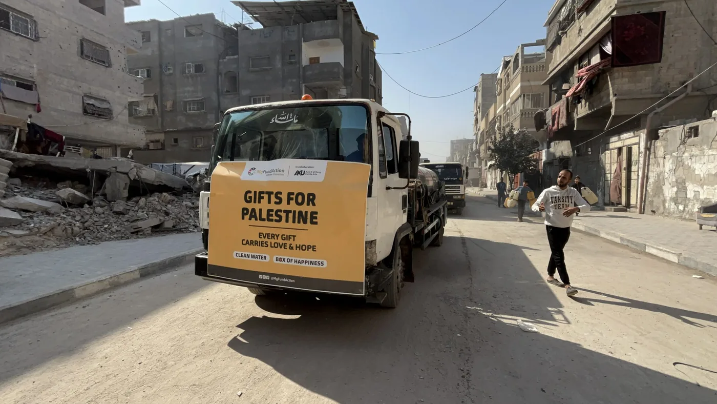 A MyFundAction 'Gifts for Palestine' aid truck driving through a damaged street in Gaza