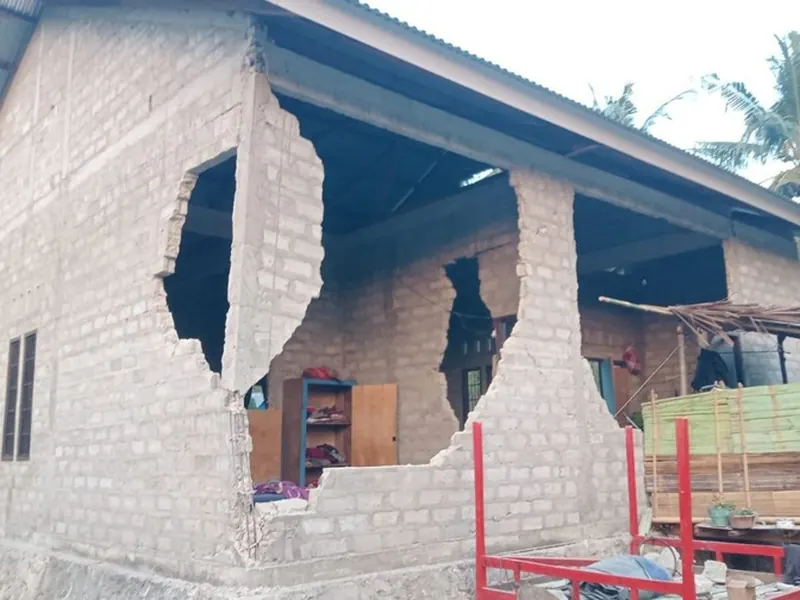 A house in Flores with its block walls broken open by the earthquake, the rooms inside exposed