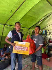 A MyFundAction team member handing a relief parcel to a man in a shelter